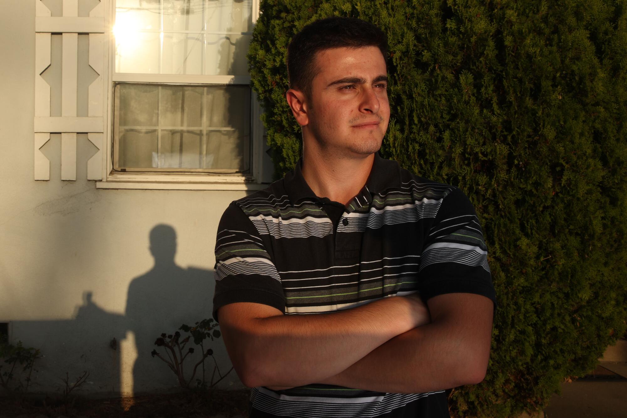 A man with arms crossed poses in front of a  window.