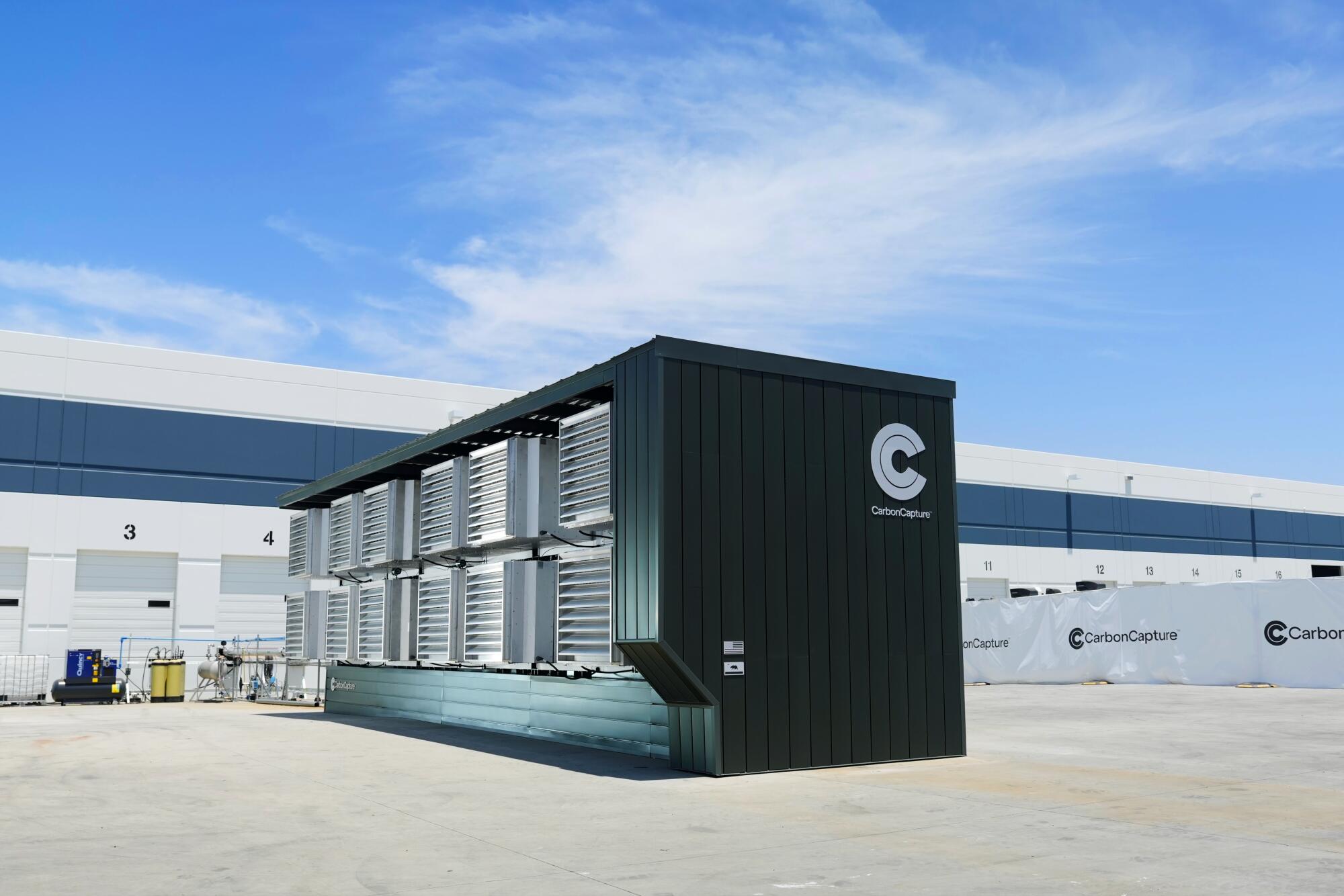 A large rectangular metal box sits outside under a blue sky.