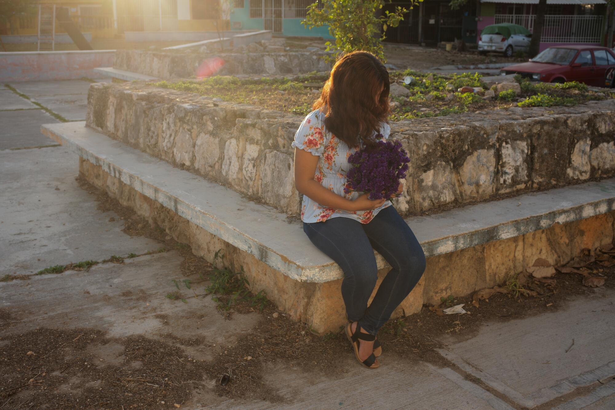 A young woman sits on a step with her hair covering her face 