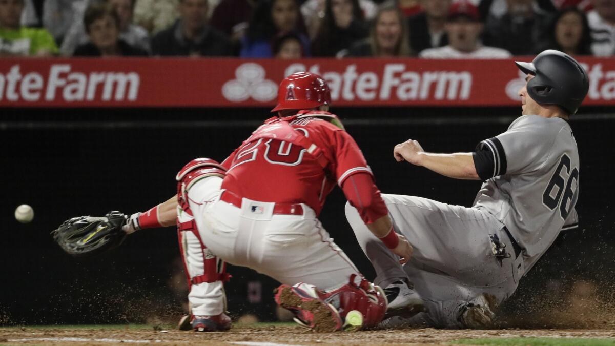 Yankees' Kyle Higashioka slides safely into home as Angels catcher Jonathan Lucroy can't hang on to the ball on a third inning sacrifice fly by first baseman Luke Voit at Angel Stadium.