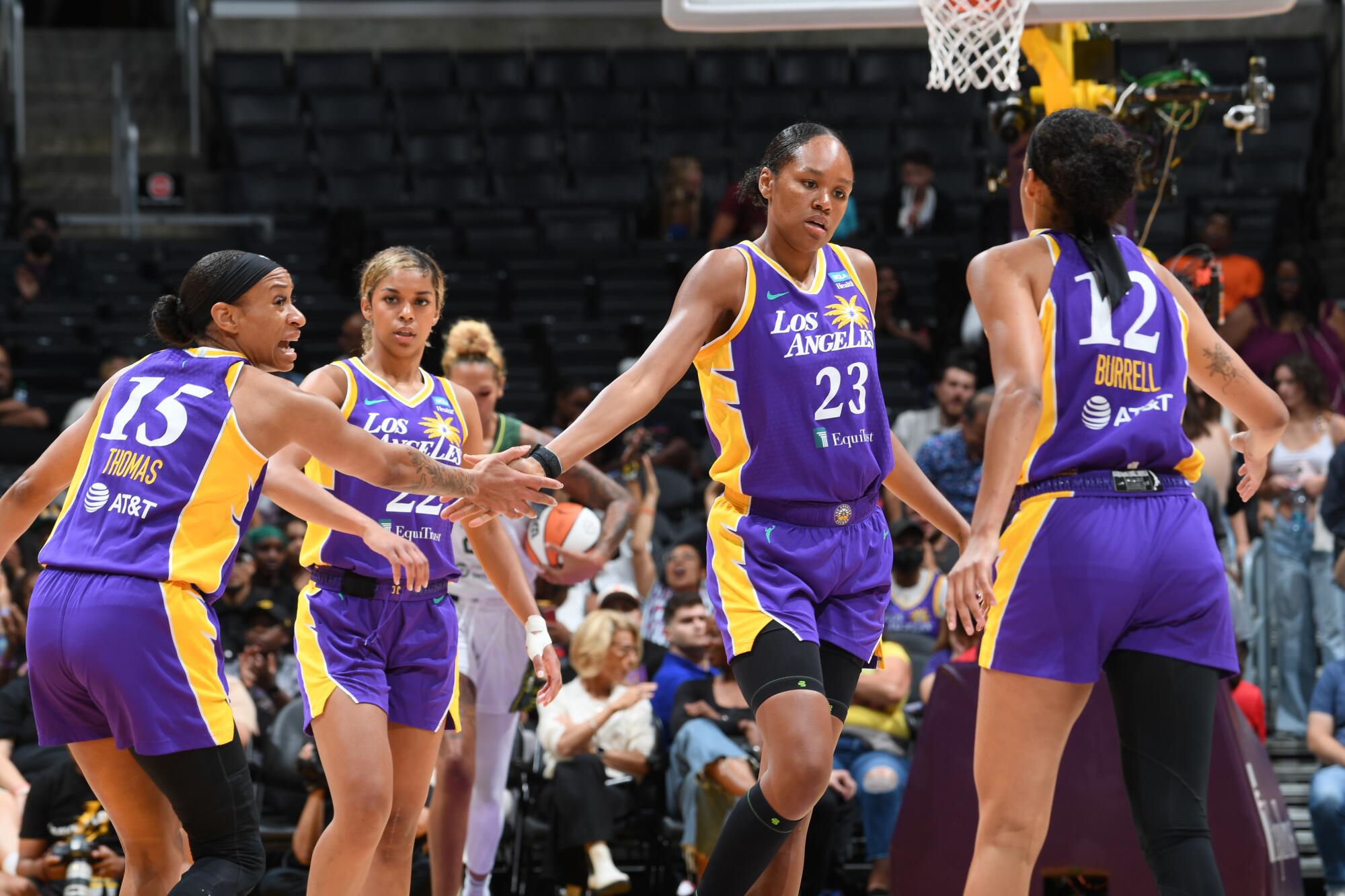 The Sparks' Jasmine Thomas (15) and Azura Stevens (23) slap hands in front of teammates Rae Burrell (12) and Evina Westbrook.