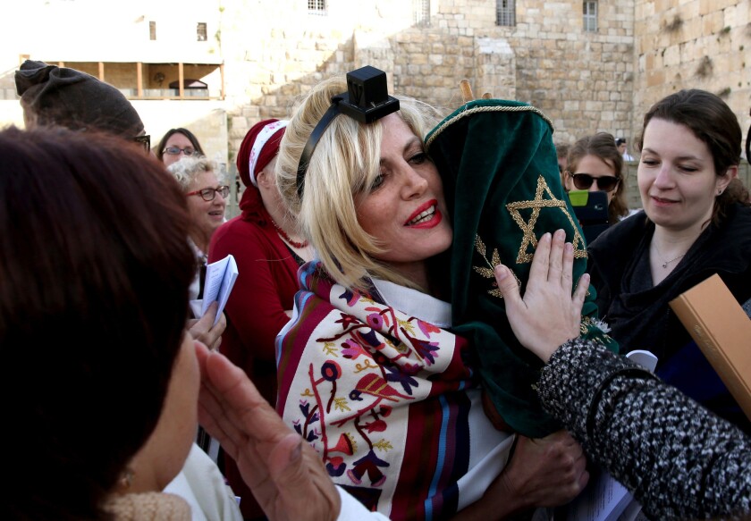 A member of the Jewish religious group Women of the Wall wears phylacteries and a traditional prayer shawl as she holds a Torah scroll at the Western Wall in Jerusalem in March.