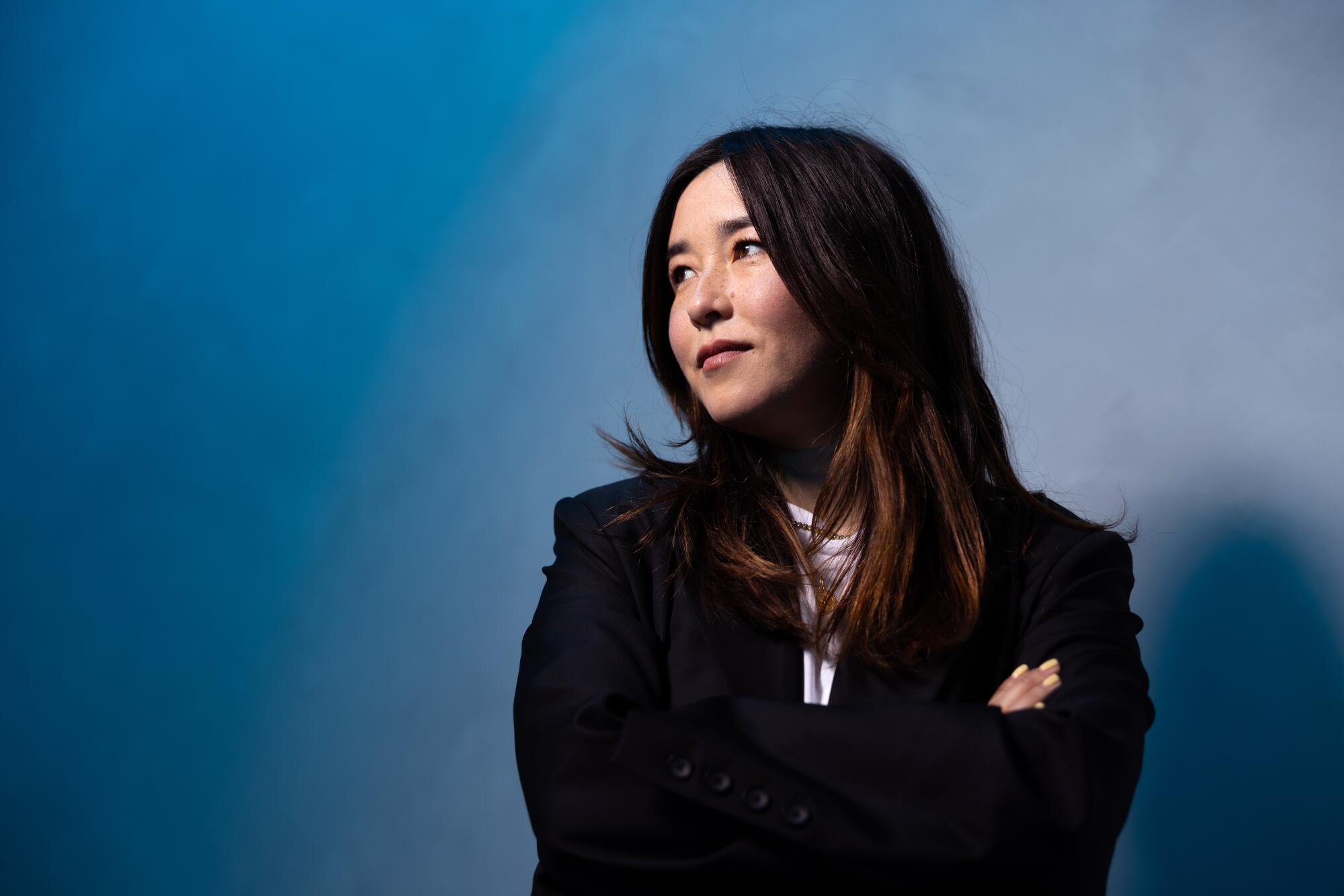 Maya Erskine crosses her arms and looks to the side for a portrait.