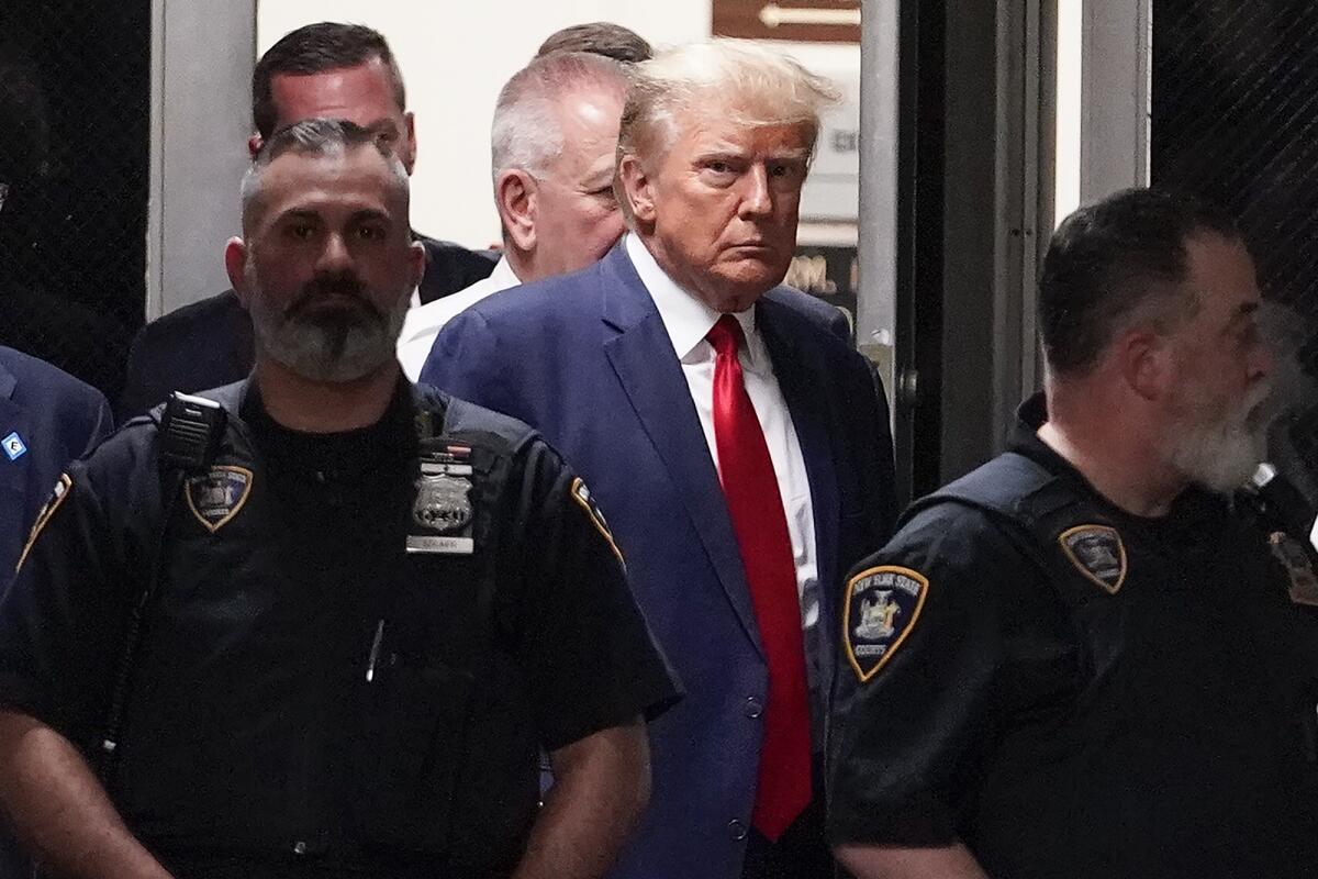Donald Trump with two law enforcement officers on either side. 
