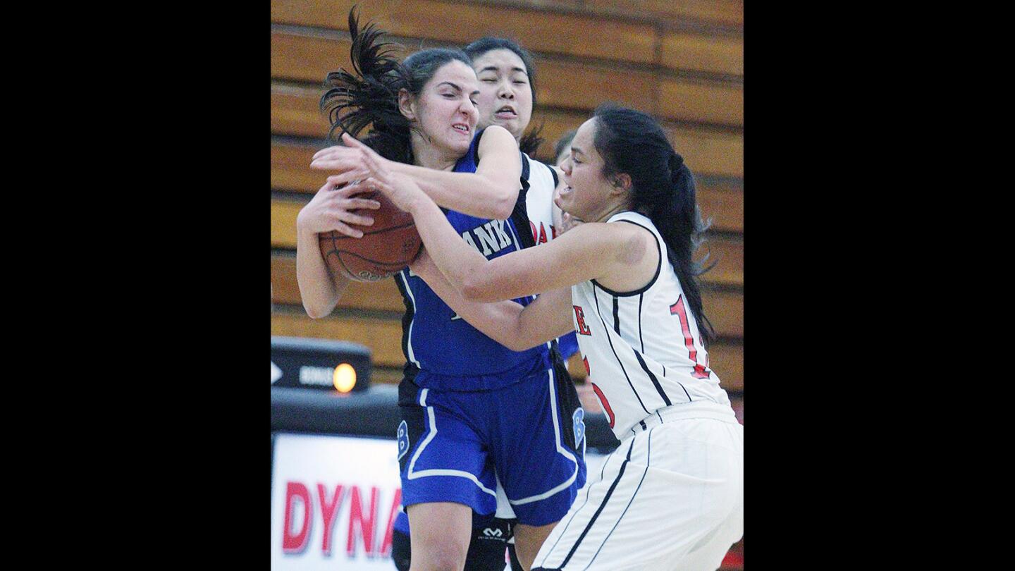 Burbank's Stephanie Grigorian gets tied up in the defense of Glendale's Merina Latu in a Pacific League girls' basketball game at Glendale High School on Wednesday, Feb. 3, 2016.