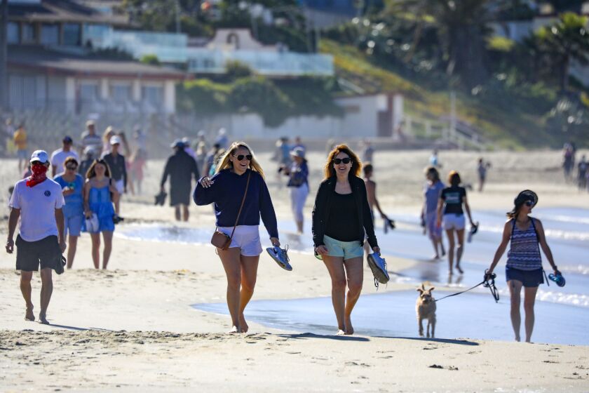LAGUNA BEACH, CA - MAY 05: People stroll along Laguna Beach on Tuesday morning as city with State's blessings reopened its beaches for active use only. The first phase of the reopening includes 6-10 a.m. hours Mondays through Fridays. in Laguna Beach on Tuesday, May 5, 2020 in Laguna Beach, CA. (Irfan Khan / Los Angeles Times)