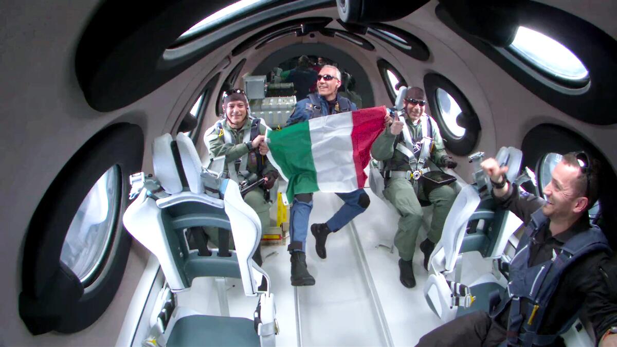 Italian researchers hold up an Italian flag inside the Virgin Galactic spacecraft