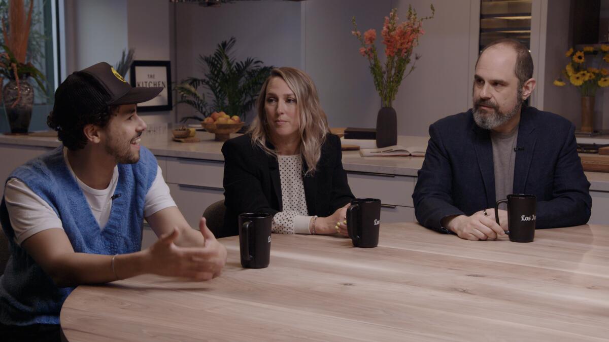 Two men and a woman sit at a table talking