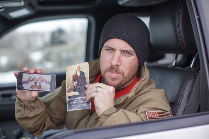 Jon Ritzheimer, 32, shows a family picture on his phone and a copy of the Constitution to the media at the Malheur National Wildlife Refuge headquarters in Oregon on Jan. 4.