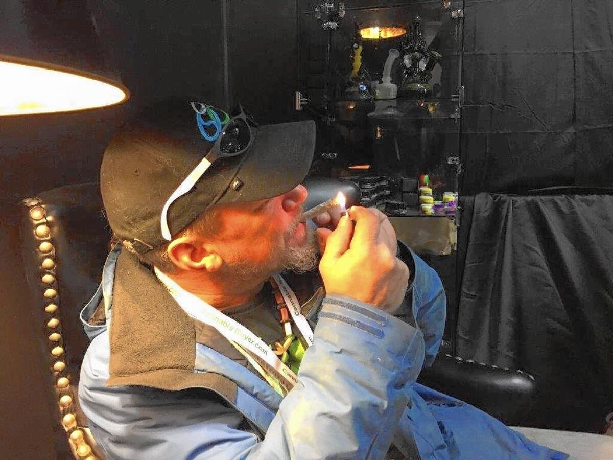 In the Aficionado booth, a Humboldt County cannabis grower, who would only identify himself as "Jefe" lights up a fat joint that he's just rolled.