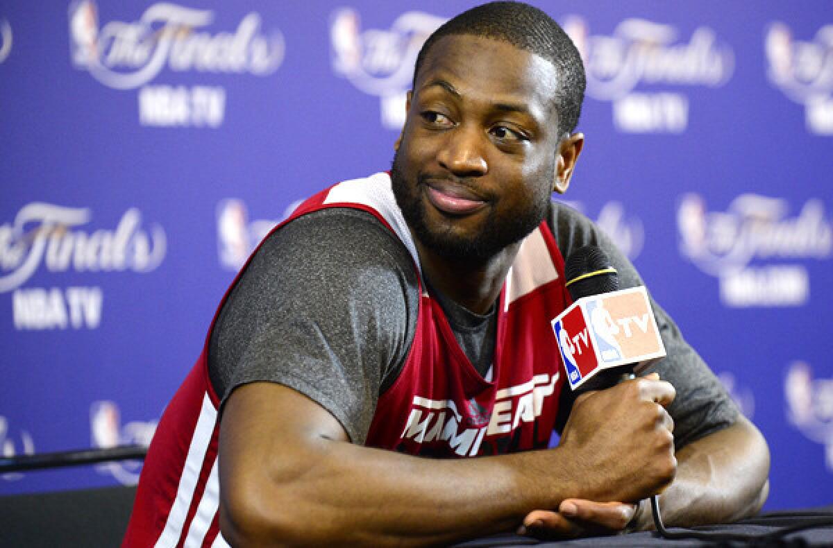 Heat guard Dwyane Wade glances toward teammate LeBron James, who was recording a video of Wade's visit with reporters Saturday.