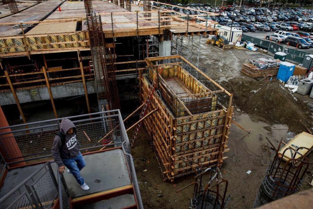 A pedestrian walks down the stairs of a garage as construction continues to add more parking spots at Cal State L.A.