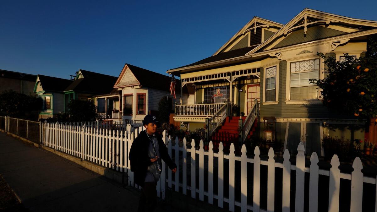 A pedestrian walks by a row of Victorian houses in the Lincoln Heights neighborhood of Los Angeles.