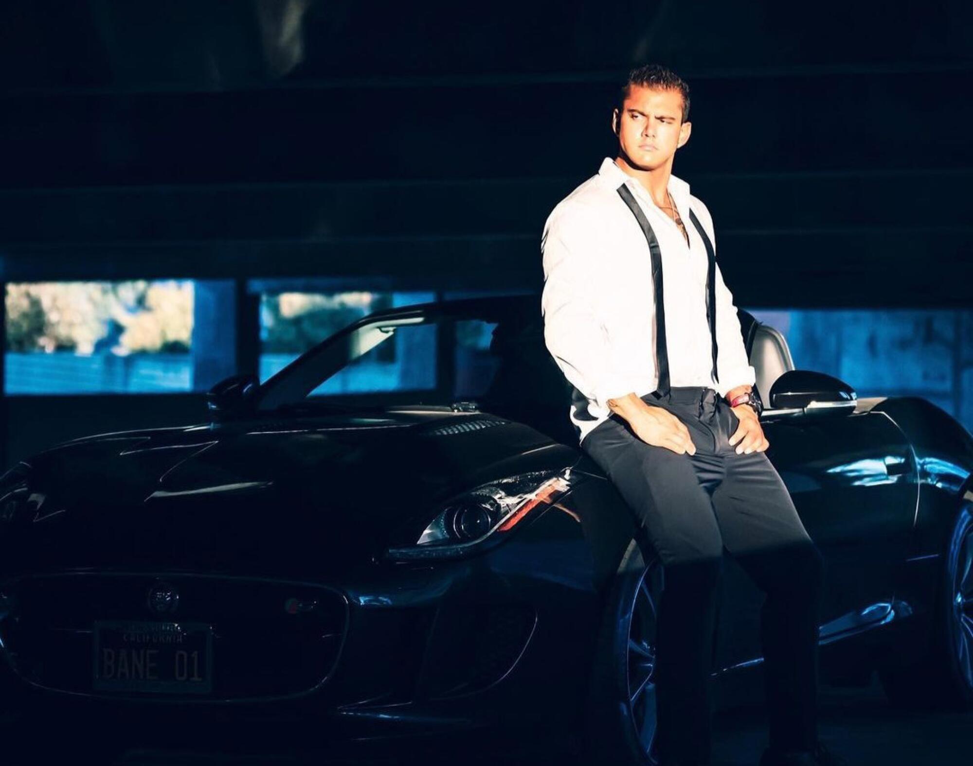 A man poses on the side of a sports car.