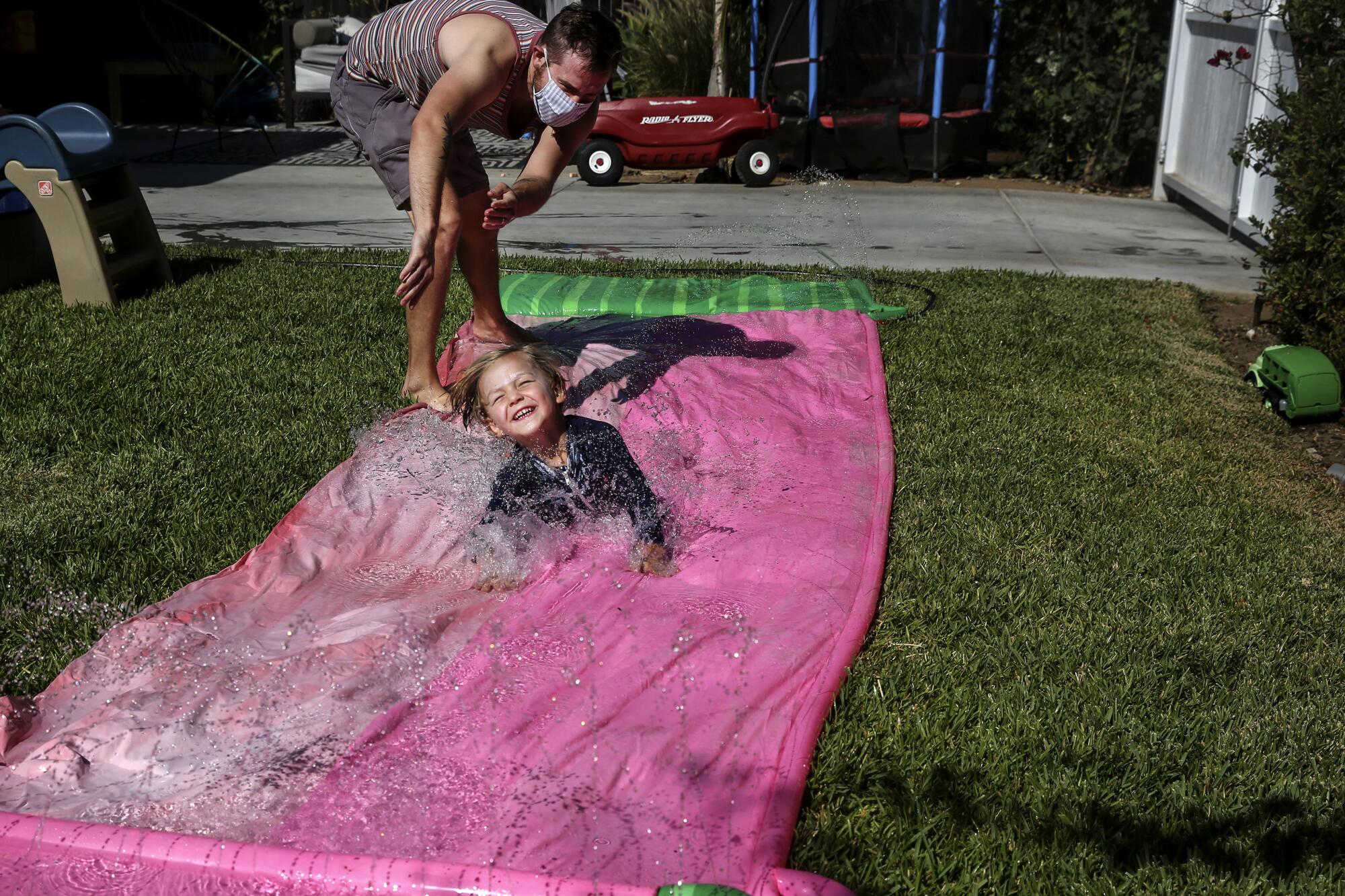 A child slides on a backyard water slide