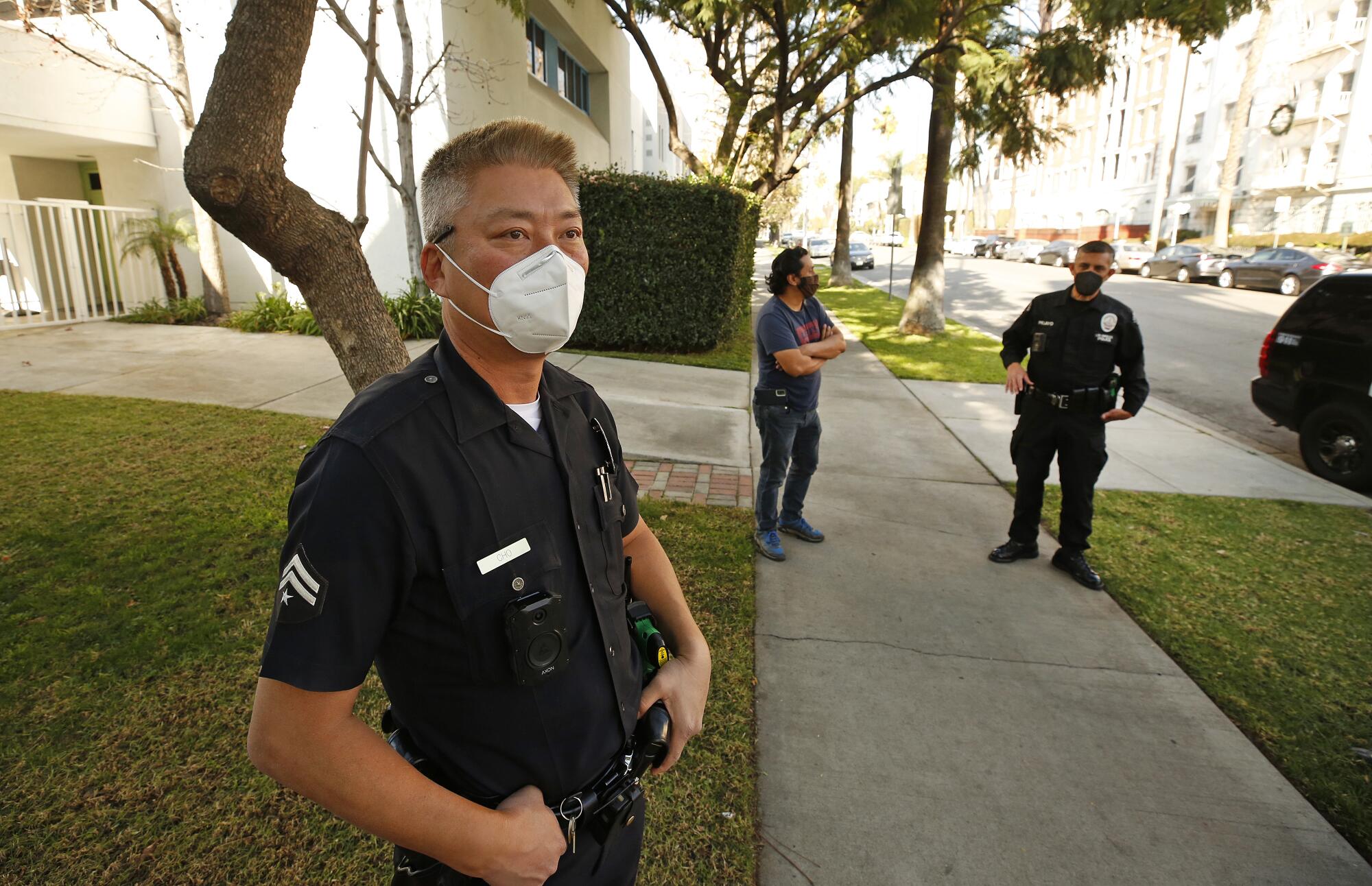 LAPD Olympic Division senior lead officers Harry Cho, left, and Joseph Pelayo talk with Byron Zapata at St James School.