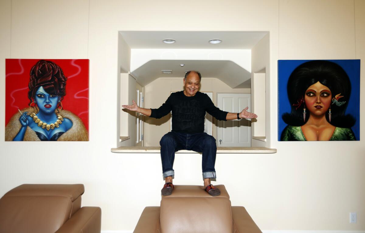 A noted art collector, Cheech Marin is flanked by a pair of paintings by Ricardo Ruiz in his Pacific Palisades home. (Genaro Molina / Los Angeles Times)