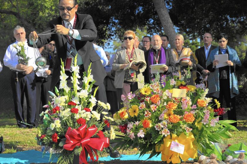 L.A. County-USC Medical Center intern chaplain Manuel Luis Torres swings an incense burner over a grave during a multi-faith ceremony remembering 1,489 individuals left unclaimed at the L.A. County Cemetery in Boyle Heights. The county has been conducting the burials since 1896.