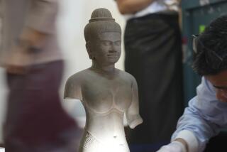 A centuries-old statue is surrounded workers preparing for a ceremony at the Cambodian National Museum,