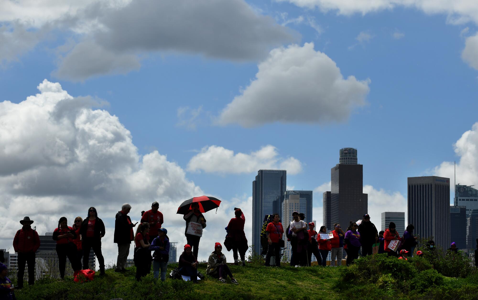 Protesters stand on a hill with downtown L.A. in the background at Los Angeles Historic State Park.