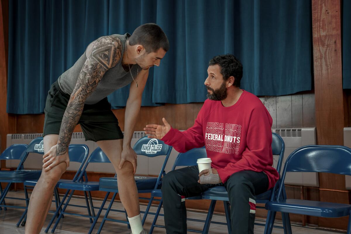  A tattooed basketball player leans down to listen to his mentor in a scene from "Hustle."