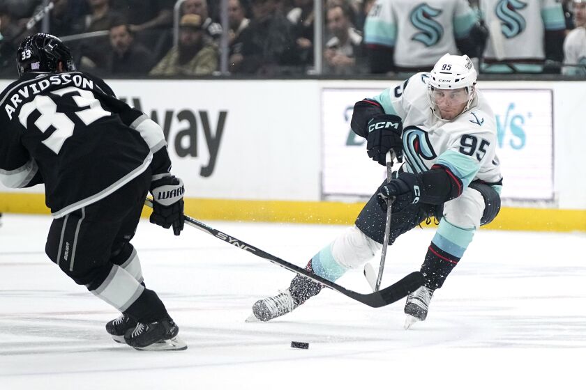 Seattle Kraken left wing Andre Burakovsky, right, passes the puck past Los Angeles Kings right wing Viktor Arvidsson during the first period of an NHL hockey game Tuesday, Nov. 29, 2022, in Los Angeles. (AP Photo/Mark J. Terrill)
