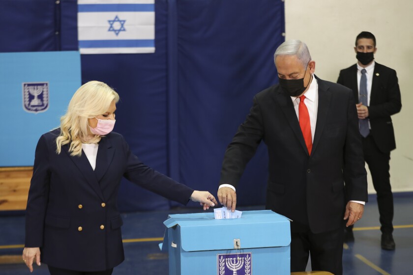 Benjamin and Sara Netanyahu drop ballots into a box.