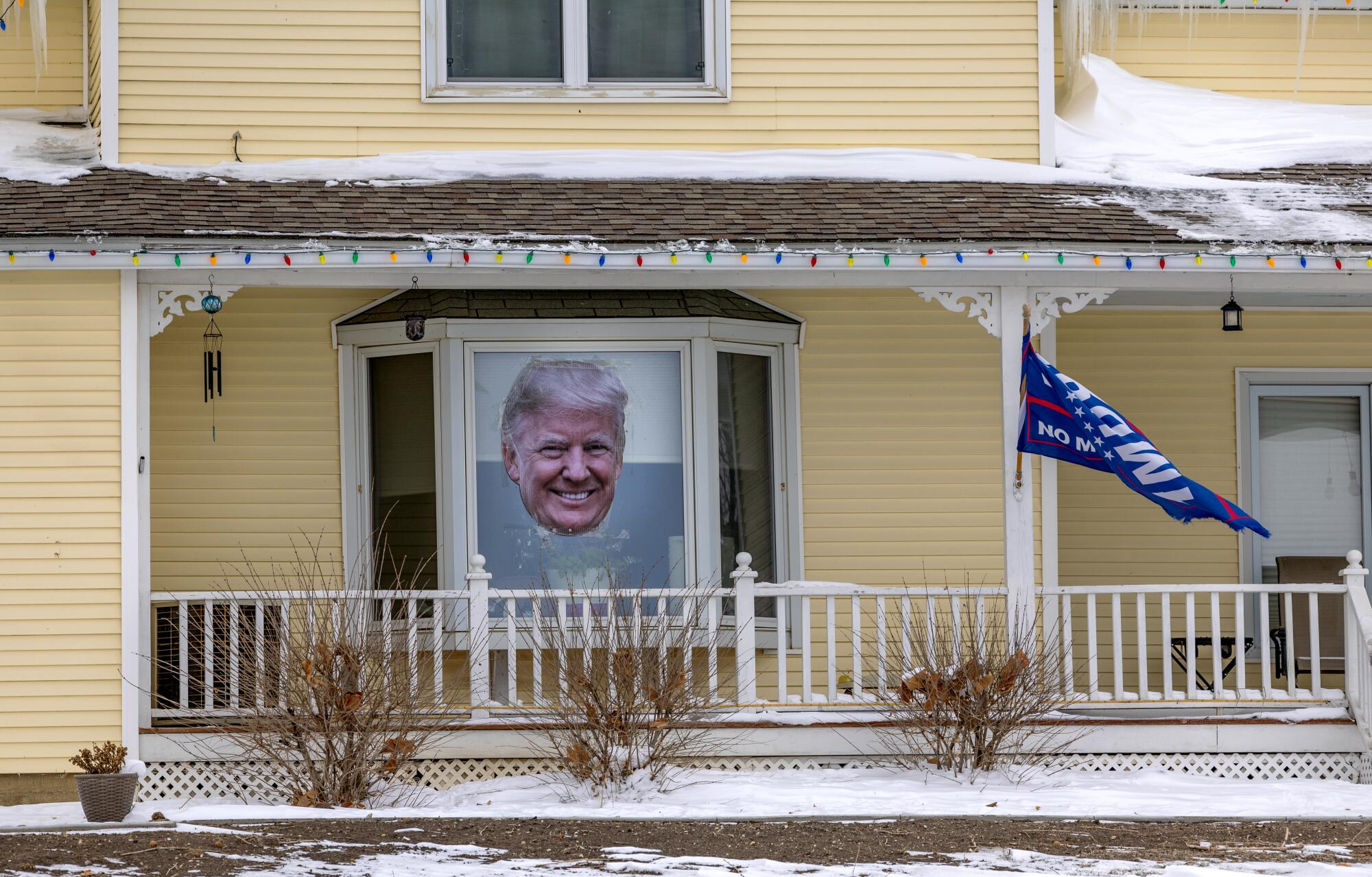 An exterior view of a home with a large photo of Donald Trump's face in the window