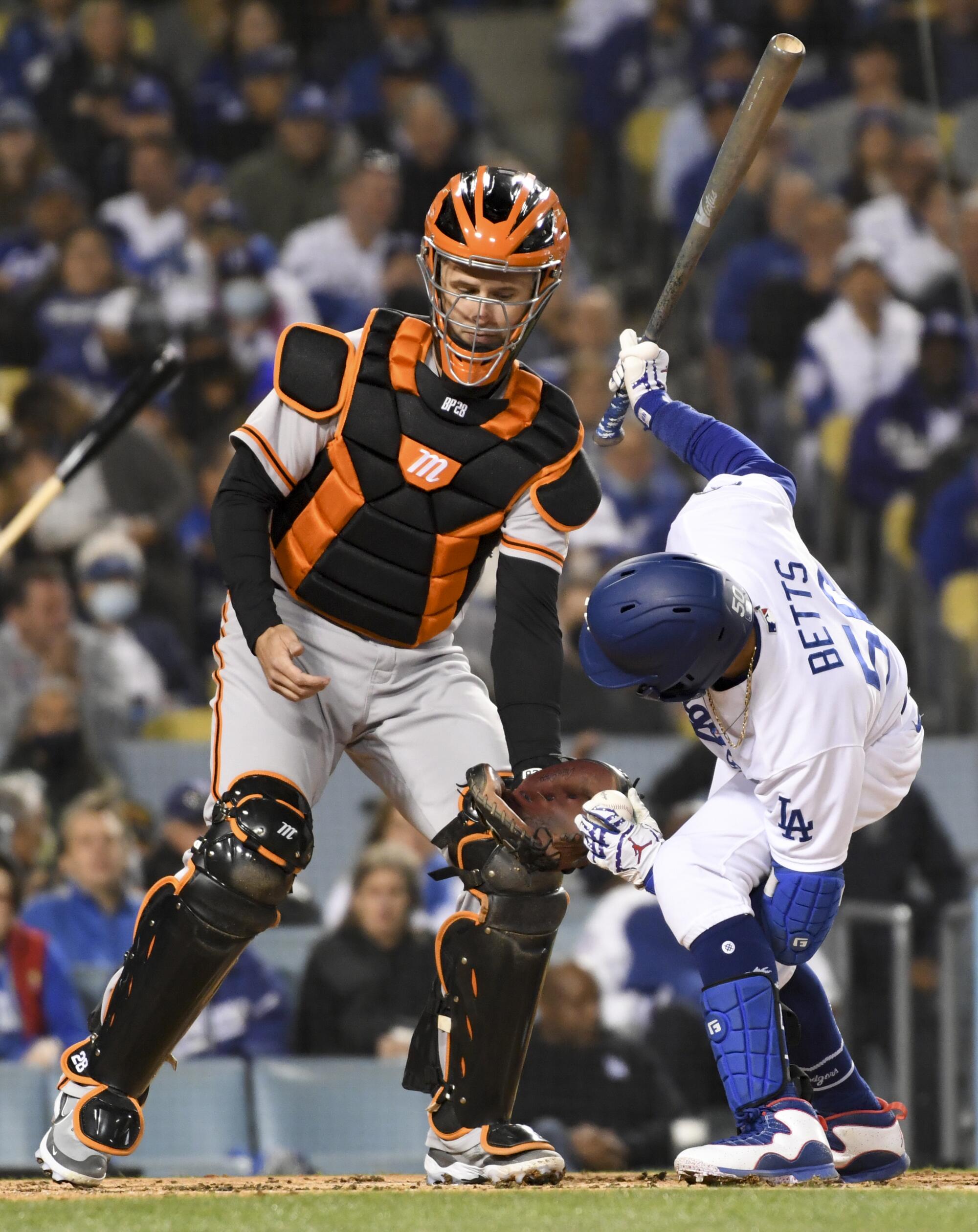Dodgers' Mookie Betts  hands the baseball between his legs to Giants catcher.