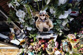 A photo of store owner Laura Ann Carleton surrounded by flowers and Pride flags and placed on memorial outside her store in the Studio City section of Los Angeles, Wednesday, Aug. 23, 2023. Authorities say a 27-year-old man was killed by California sheriff's deputies over the weekend after he fatally shot Carleton, outside her store in Cedar Glen, Calif. roughly 60 miles (96 kilometers) east of downtown Los Angeles. Investigators determined that prior to the shooting the suspect tore down a Pride, or rainbow, flag that was hanging in front of the store and yelled many homophobic slurs toward Carleton. (AP Photo/Richard Vogel)