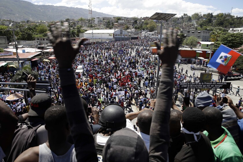 A crowd of people is seen through the upraised arms of one man.