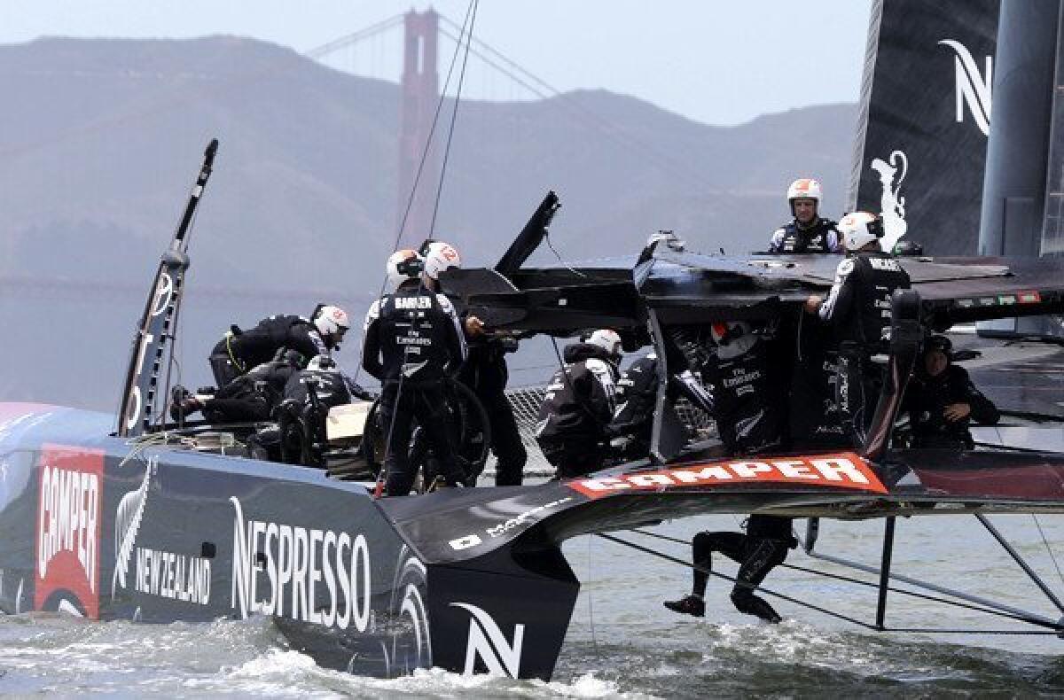 Emirates Team New Zealand crew members make repairs to their damaged catamaran following the first race of their America's Cup challenger series final on Saturday in San Francisco Bay.