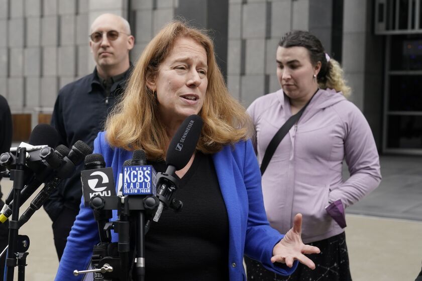 Attorney Shannon Liss-Riordan, foreground, speaks in front of former Twitter employees Dmitry Borodaenko, rear left, and Wren Turkal during a news conference outside of a federal courthouse in San Francisco, Thursday, Dec. 8, 2022. Borodaenko and Turkal are some of the former Twitter employees suing the company in federal court after losing their jobs when billionaire Elon Musk took over. (AP Photo/Jeff Chiu)