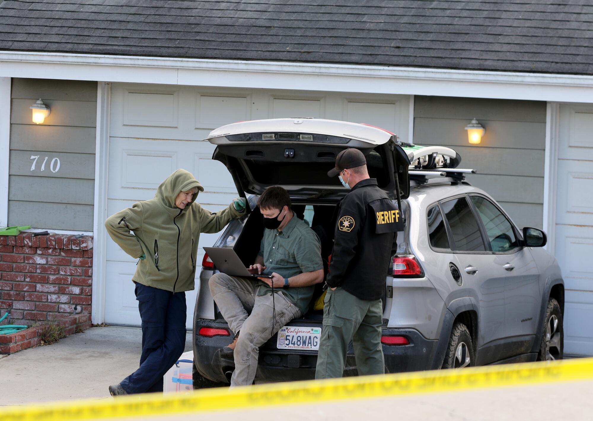 Sheriff's officials at rear of vehicle. 