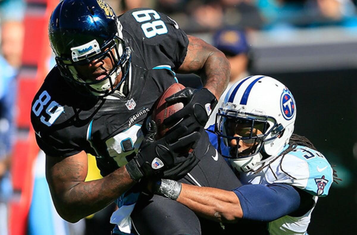 Jaguars tight end Marcedes Lewis tries to fight through a tackle by Titans defensive back Michael Griffin during a game last season.