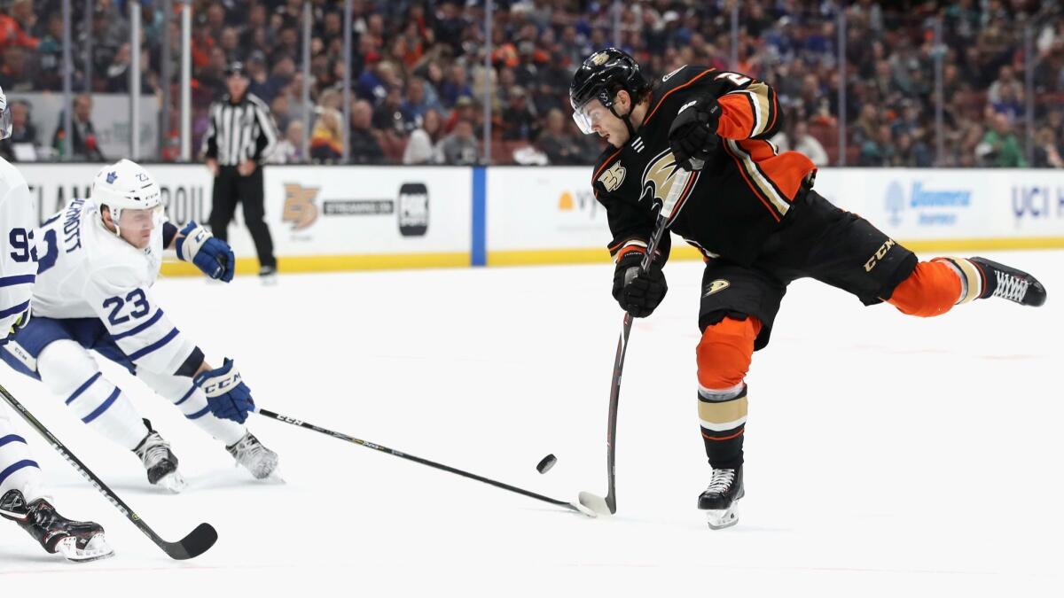 Ducks' Pontus Aberg shoots the puck as Toronto Maple Leafs' Travis Dermott defends during the third period on Friday at the Honda Center.
