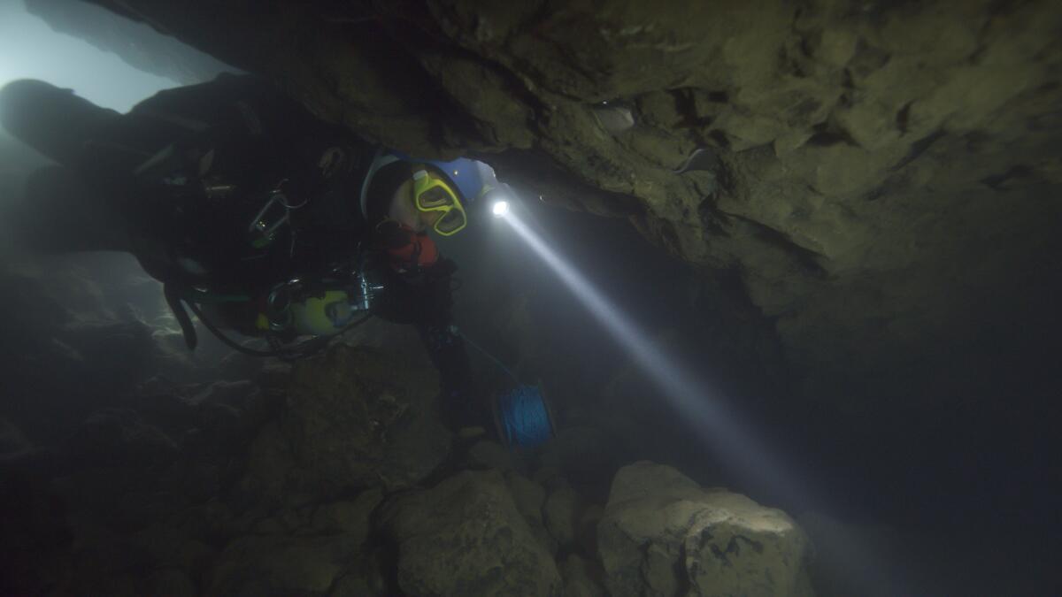 A cave diver negotiates a narrow passage.