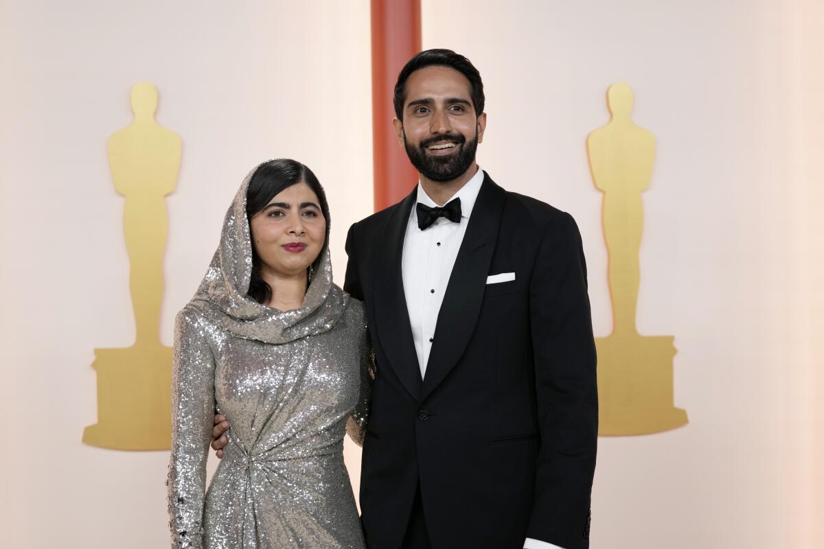 Malala Yousafzai, izquierda, y Asser Malik posan en la alfombra de los Oscars.