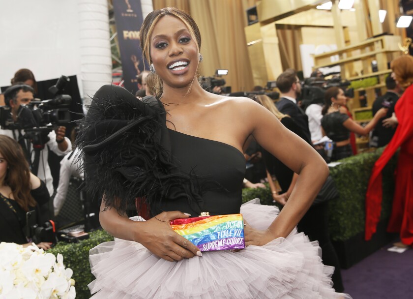 Laverne Cox in a fancy gown holding a rainbow clutch