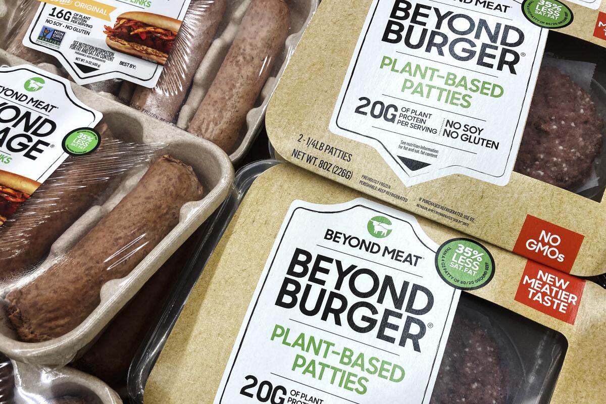 FILE - Beyond Meat products are seen in a refrigerated case inside a grocery store in Mount Prospect, Ill., Saturday, Feb. 19, 2022. Beyond Meat is cutting about 200 jobs and lowering its full-year revenue outlook as the plant-based meat maker attempts to reduce expenses and become cash flow positive. The company said Friday, Oct. 14, the job cuts, which amount to approximately 19% of its total global workforce, will be mostly completed by the end of the year. (AP Photo/Nam Y. Huh, File)