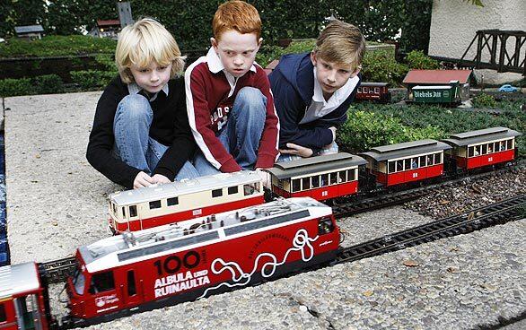 Jack and Paulette Lantz share their Pasadena home, a Buff & Hensman beauty, with a collection of Asian antiquities and with Jack's beloved model trains. He's happy to let others in on the fun. Here, from left, Tex Meyers, Ryan Purdy and Christian Gropper get down to rail level to watch trains move through the yard.