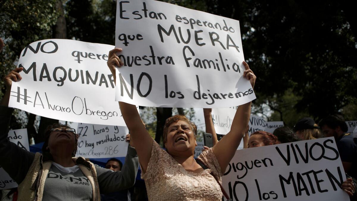 Family members holding signs that read in Spanish "They are waiting for our family to die," "They are still alive. Don't kill them" and "No heavy machinery" protest outside a quake-collapsed seven-story building in Mexico City's Roma Norte neighborhood Friday.