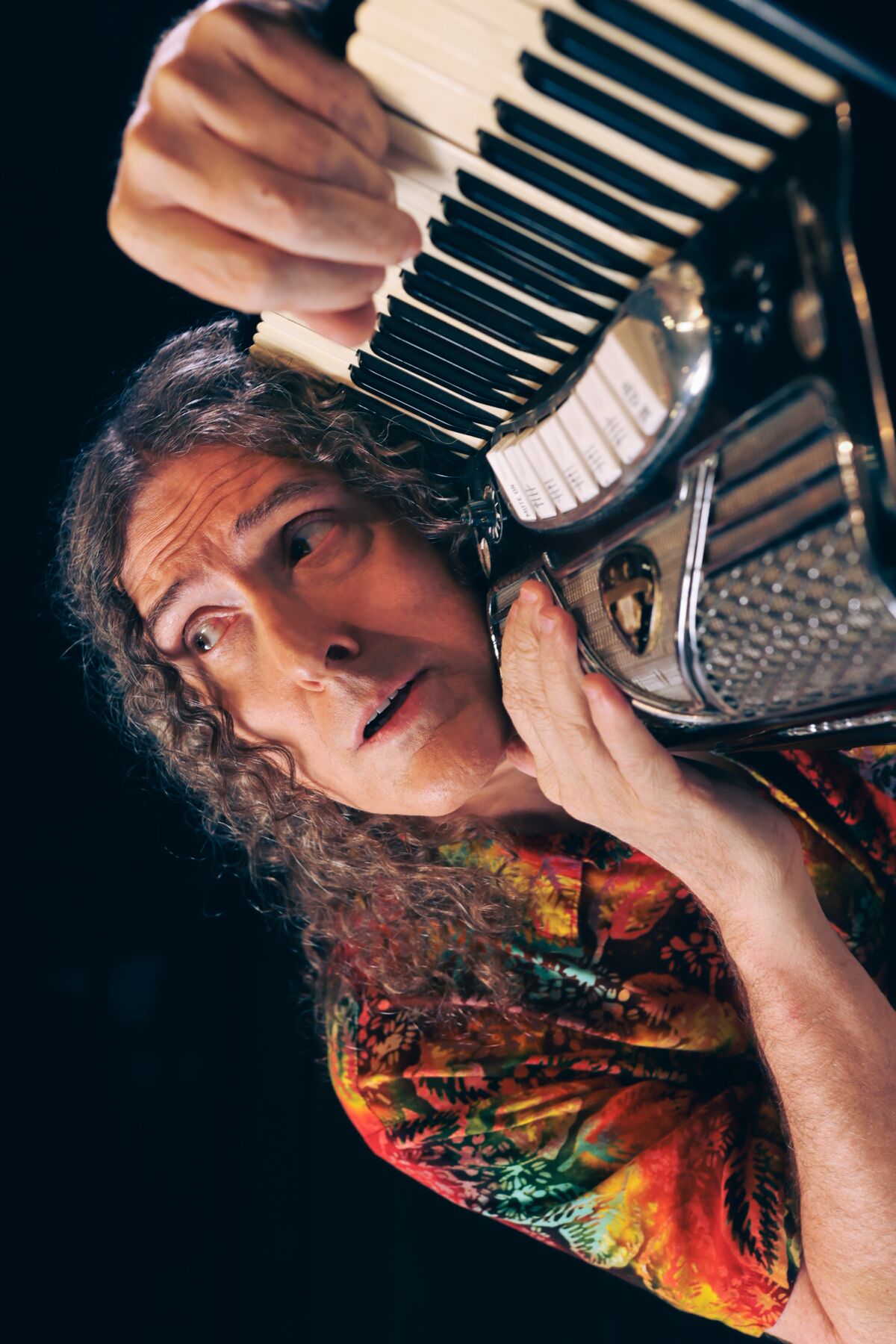 A man lovingly embracing his accordion, staring emotively off in space