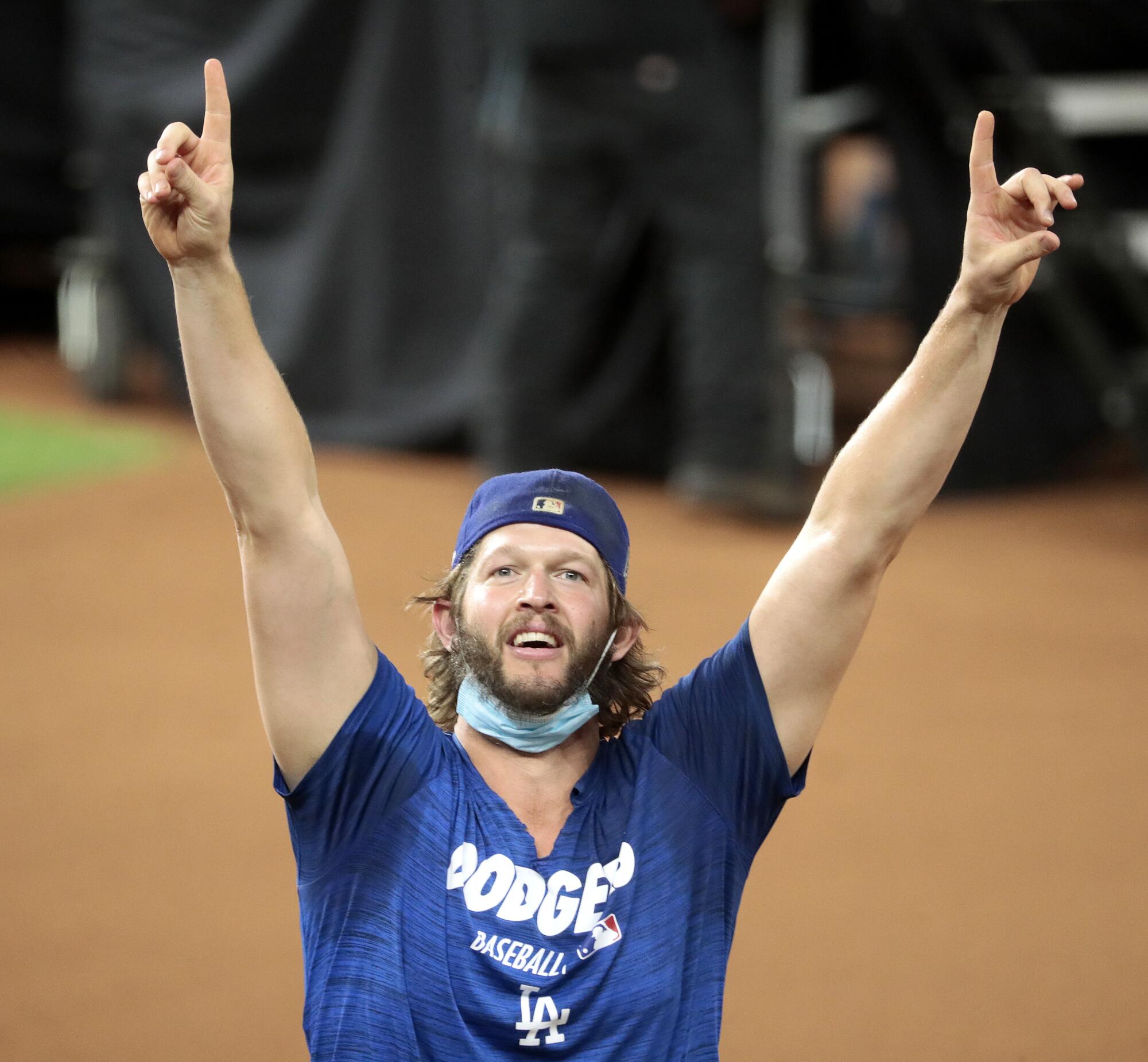Clayton Kershaw runs onto the field with both arms raised.