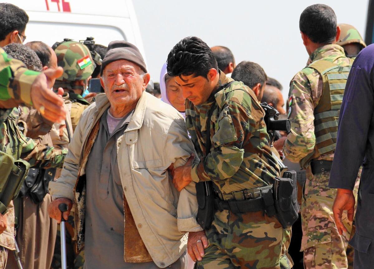 Kurdish peshmerga forces help people from Iraq's Yazidi minority in the village of Humeira, southwest of Kirkuk, on April 8, 2015 after they were released by Islamic State.