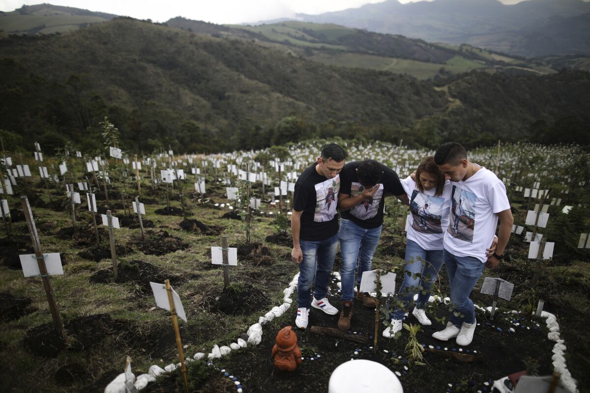 Relatives of Luis Enrique Rodriguez, who died of COVID-19, visit where he was buried on a hill 
