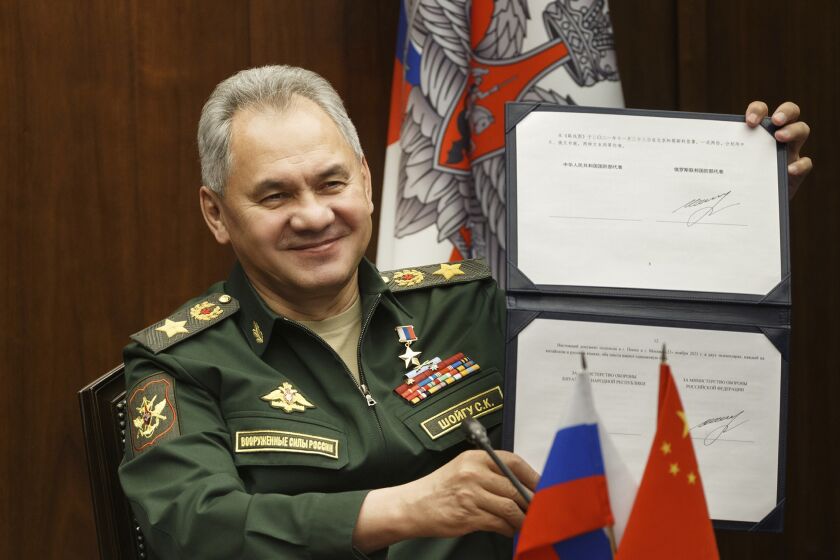 In this photo released by the Russian Defense Ministry Press Service, Russian Defense Minister Sergei Shoigu shows his signature under a roadmap for military cooperation between Russia and China during a video call with Chinese Defense Minister Wei Fenghe in Moscow, Russia, Tuesday, Nov. 23, 2021. Shoigu and Wei signed a roadmap for military cooperation between Moscow and Beijing and called for intensifying joint drills and patrols. (Vadim Savitskiy/Russian Defense Ministry Press Service via AP)