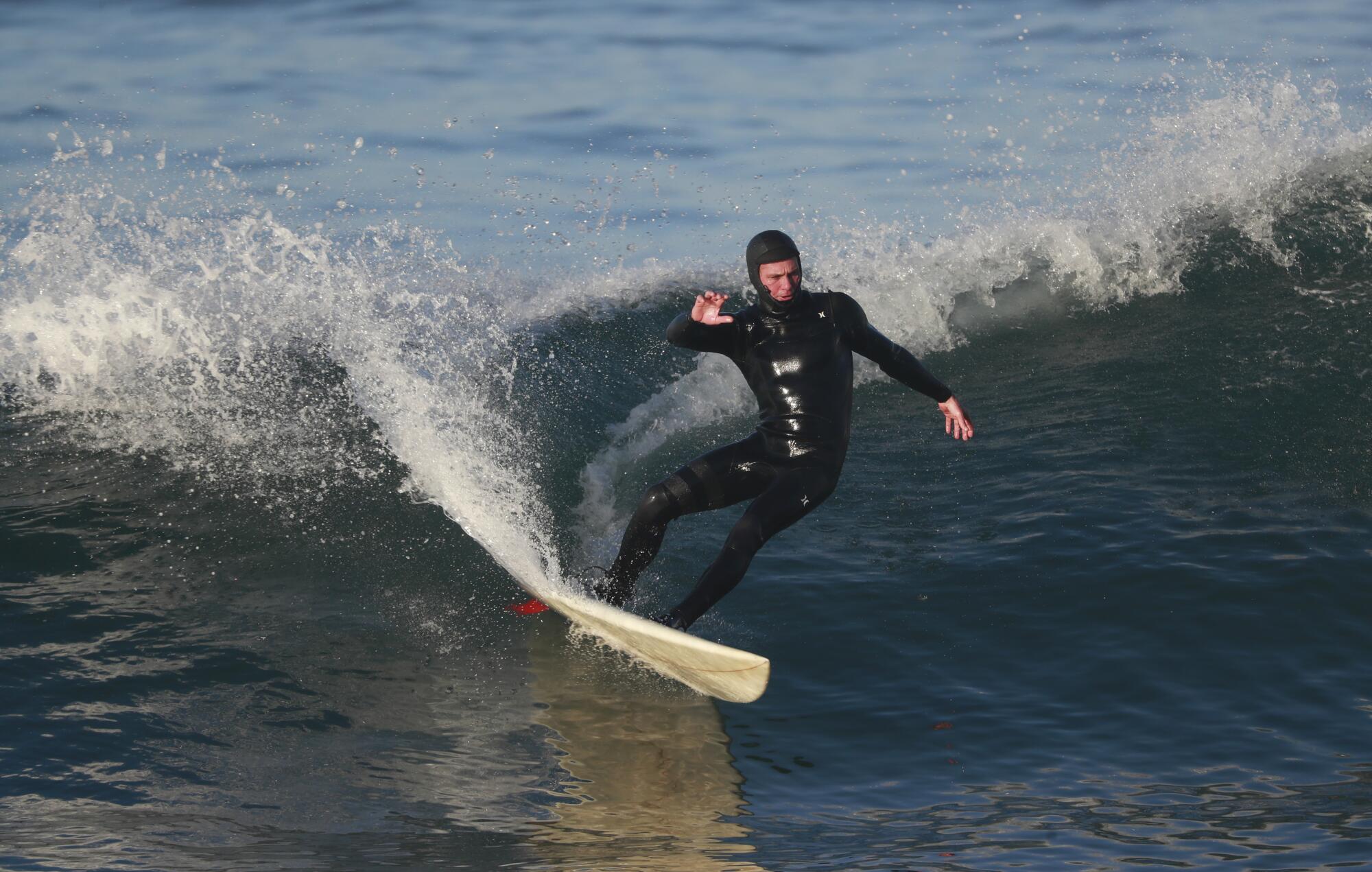 A man in a wetsuit rides a surfboard