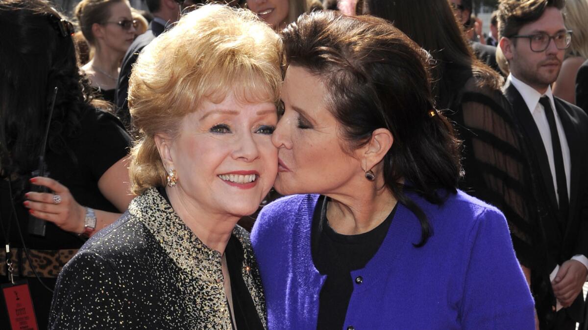 Carrie Fisher kisses her mother, Debbie Reynolds, as they arrive at the Primetime Creative Arts Emmy Awards in Los Angeles in 2011.