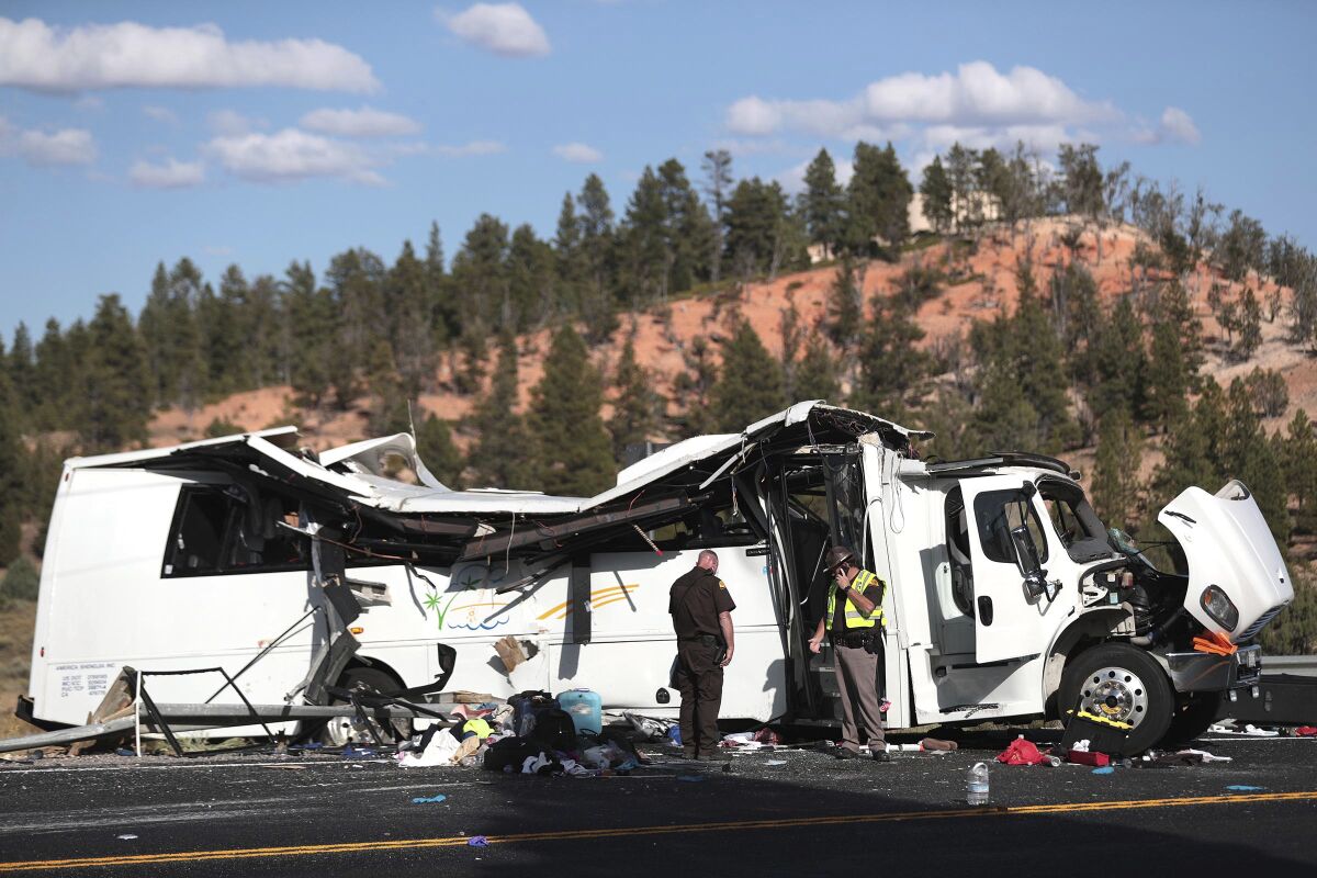 FILE - In this Sept. 20, 2019, file photo, authorities work the scene of a tour bus crash near Bryce Canyon National Park in Utah. The families of Chinese tourists killed or injured in the crash say the state's design and maintenance failed to keep the remote highway safe. (Spenser Heaps/The Deseret News via AP, File)